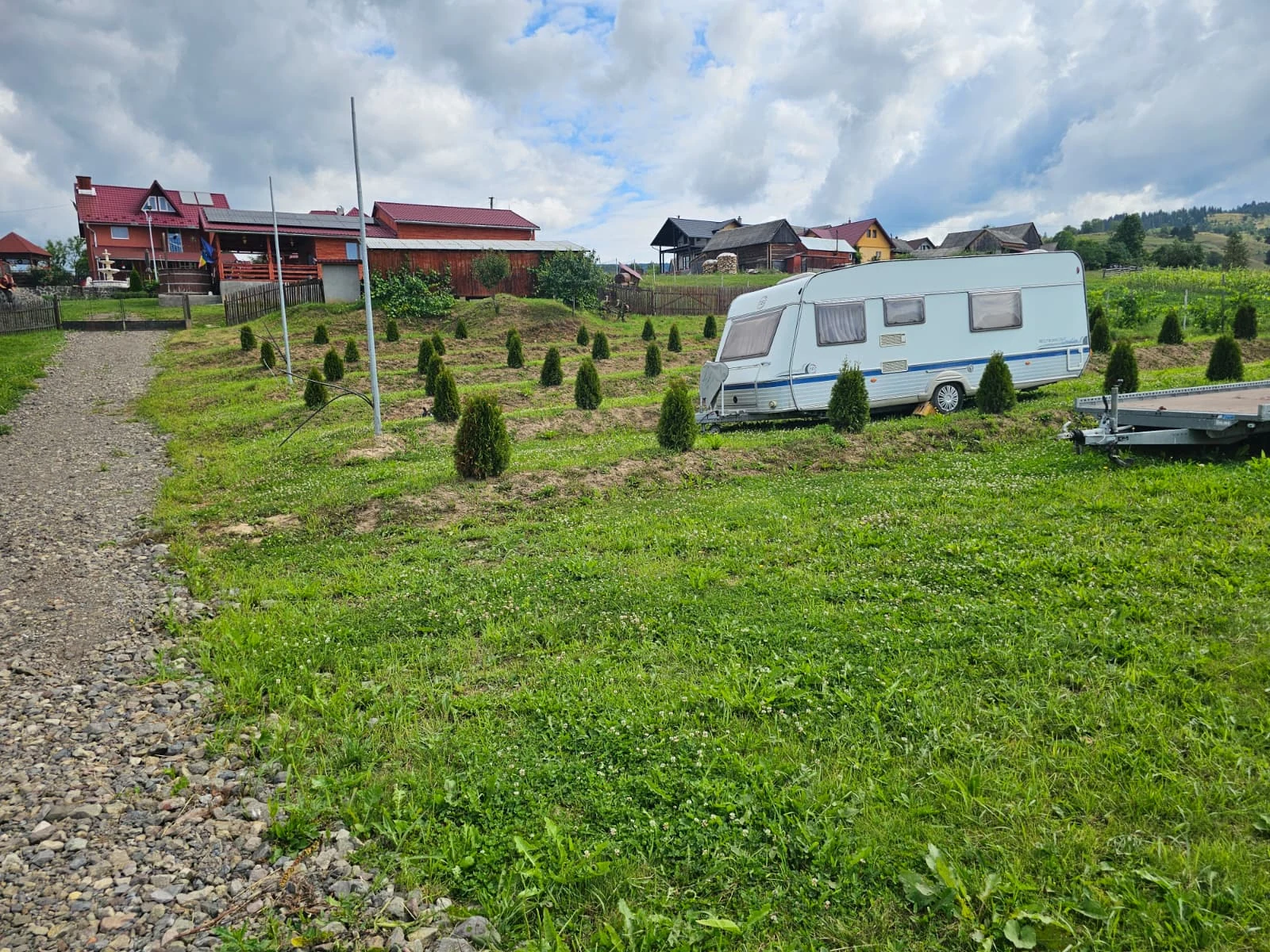 Rulotă amplasată în camping, cu pensiunea în fundal